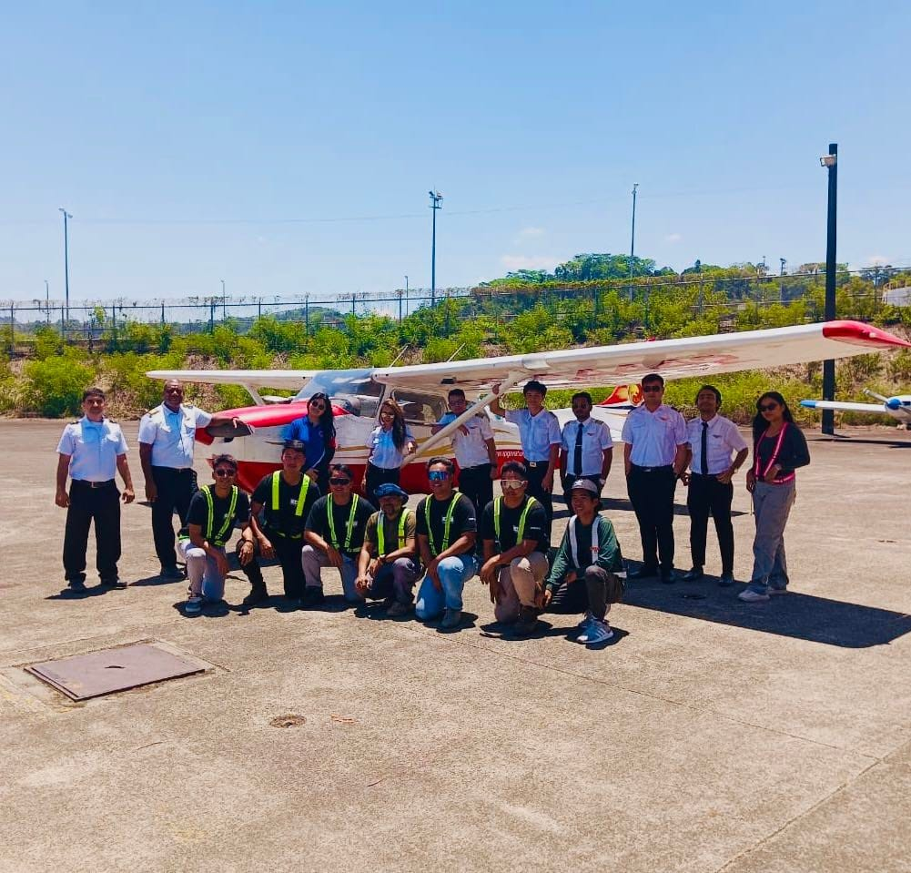 Group of students and instructors posing with a training aircraft